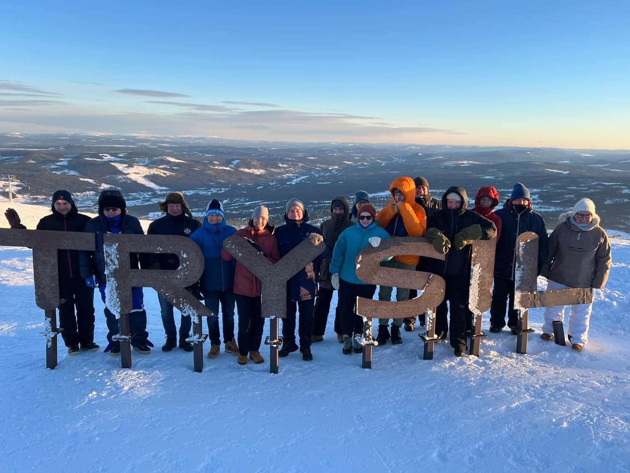 Gruppe med mennesker på et fjell fremfor bokstavene Trysil