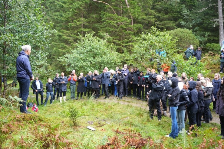 Mange glade menneskje i skogen der ein mann set ned eit skilt