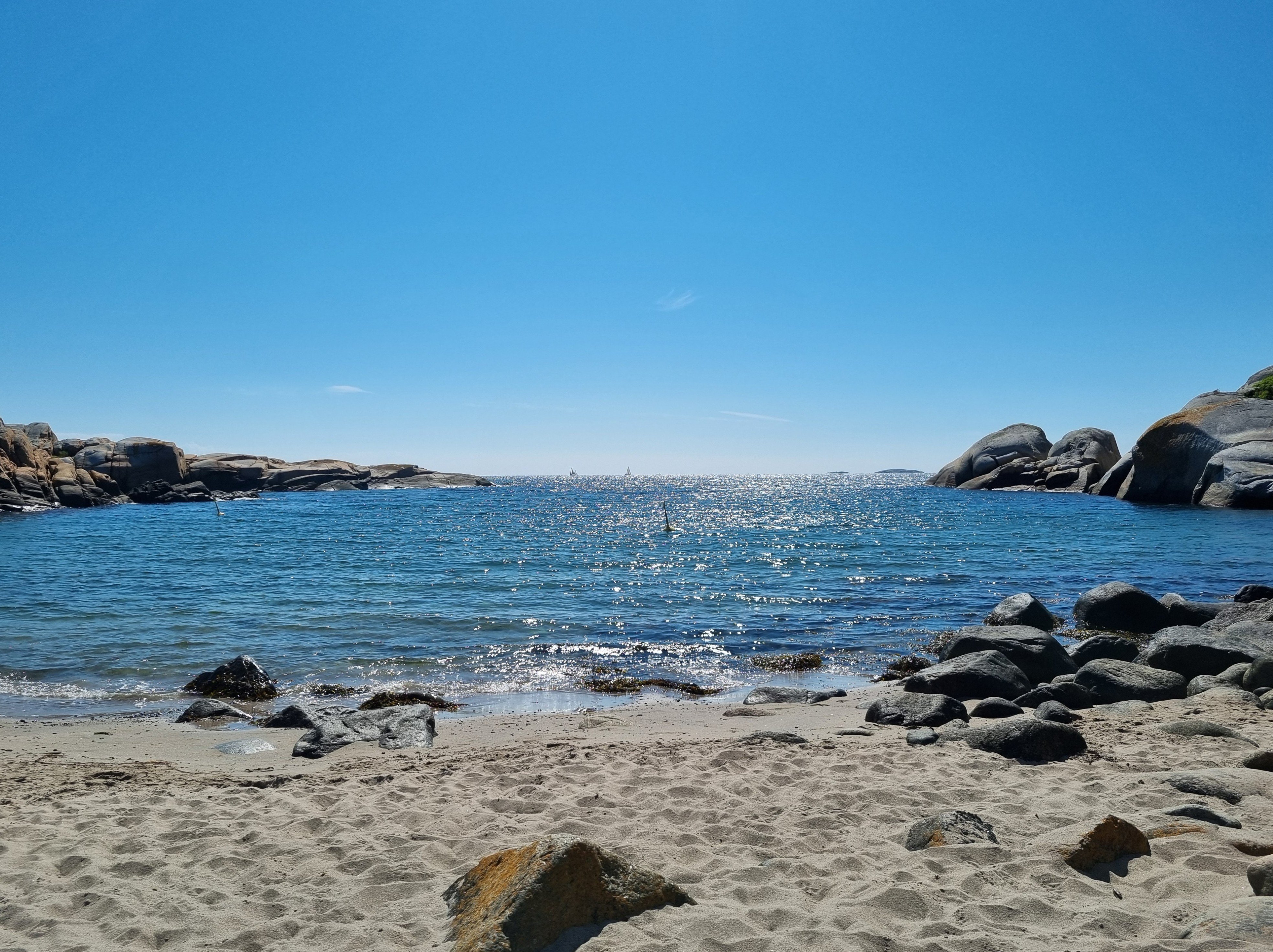 Sandstrand, vann og blå himmel