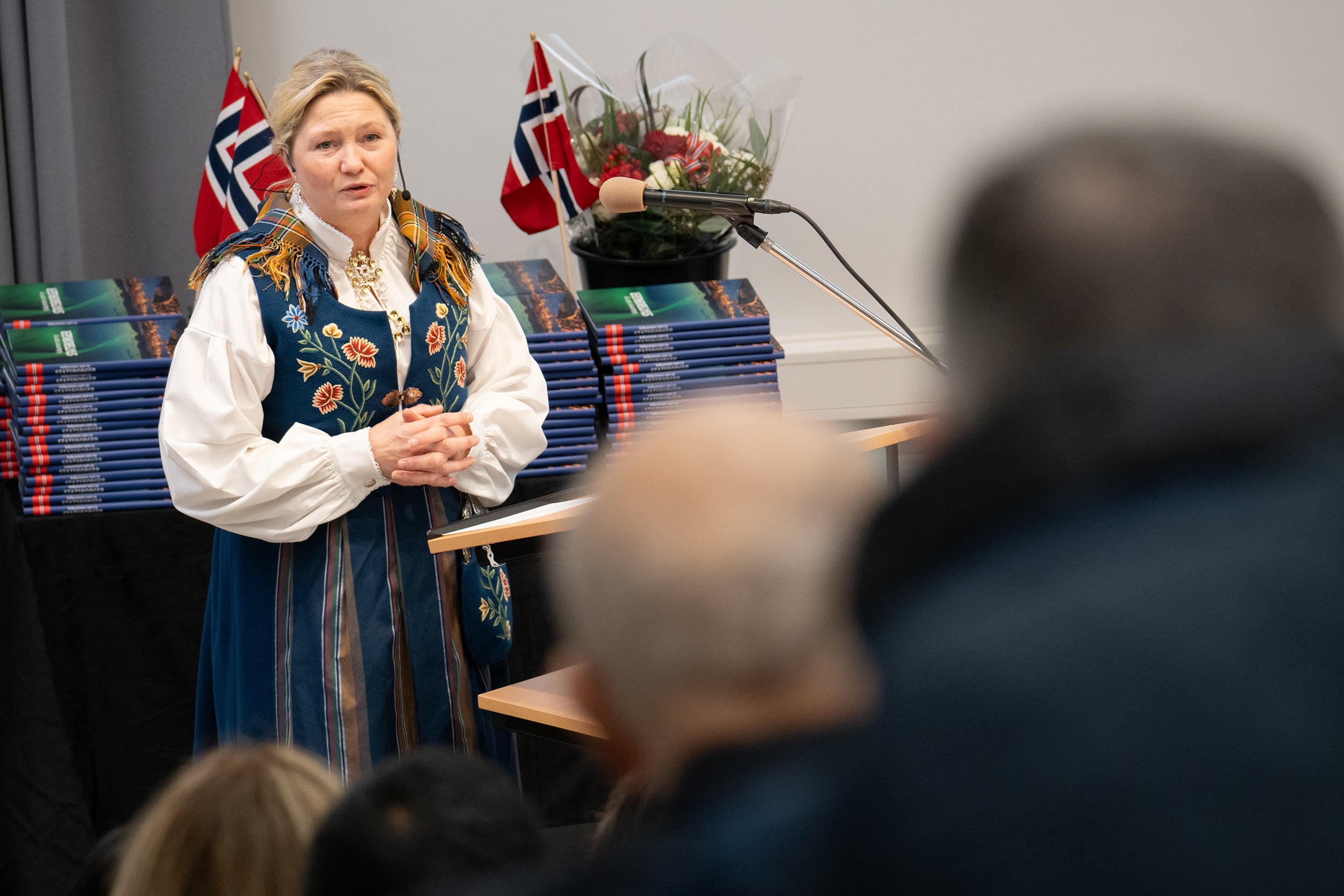 Kvinne i nordlandsbunad taler til forsamling.