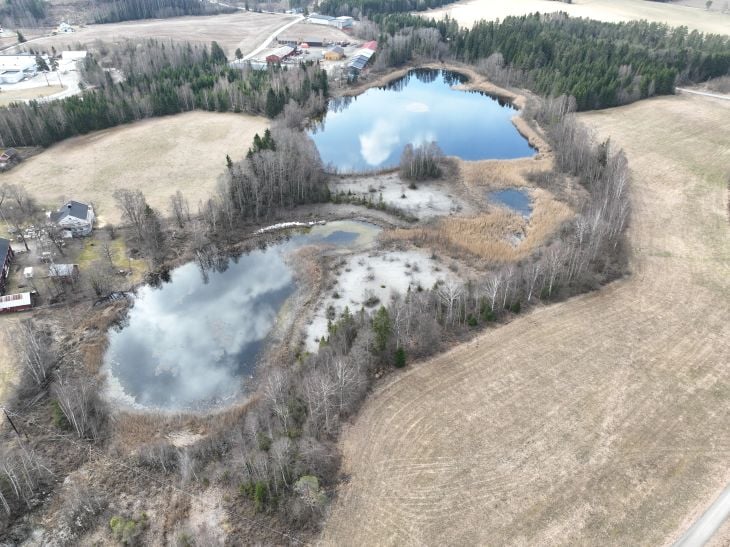 Foto av tjern, skog og jorder.