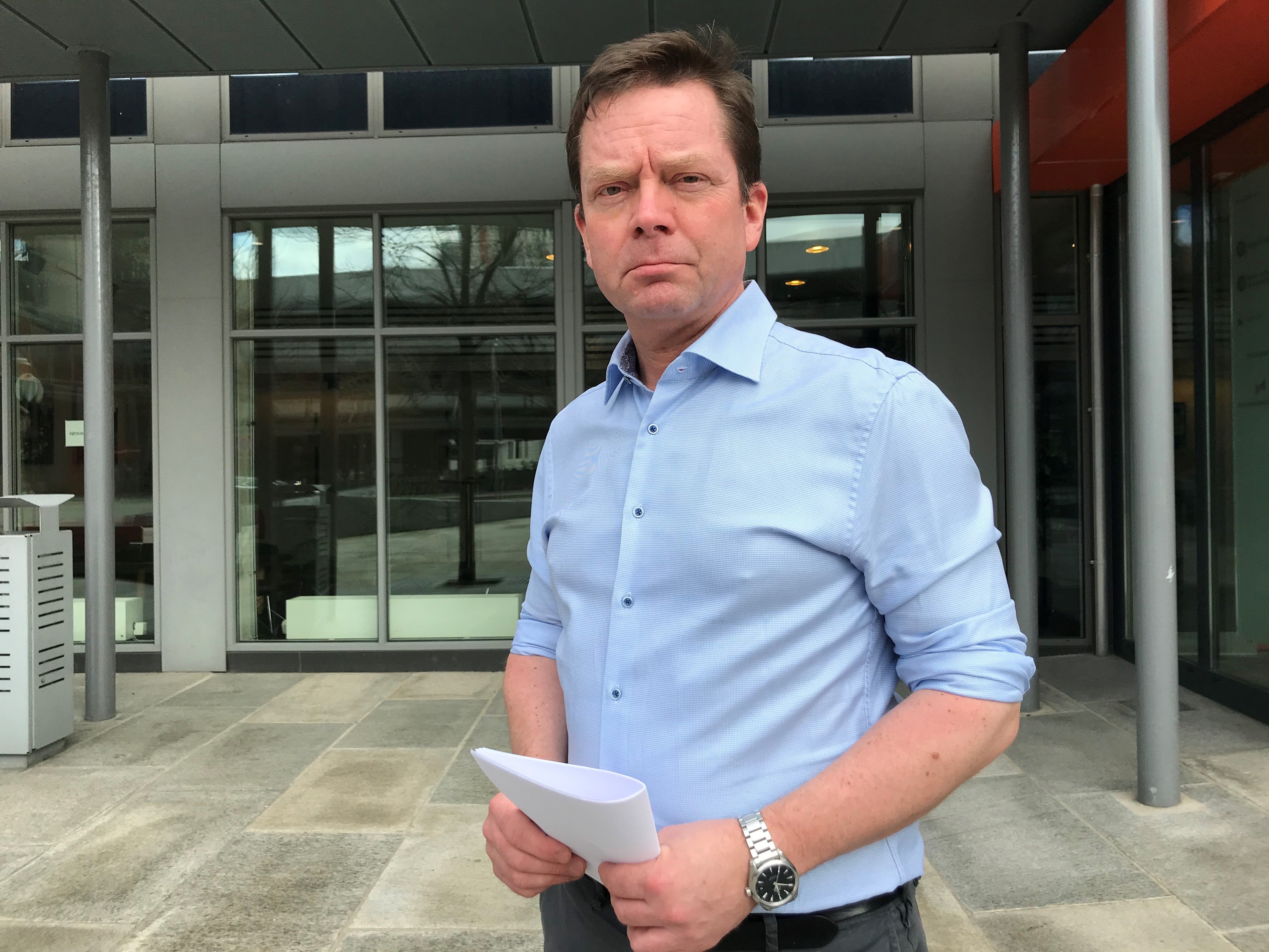 Fylkeslege Sjur Lehmann foran Statens hus medan han held i ein bunke papir.