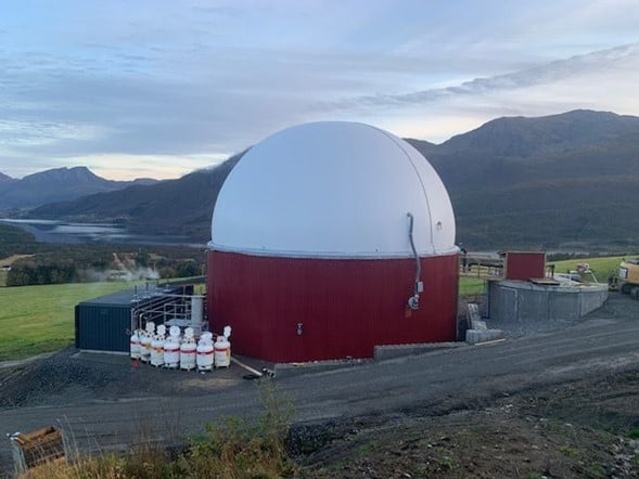 I blandekummen til høgre vert husdyrgjødsel og anna substrat blanda. Biogassreaktorkuppelen ser vi i midten, og containerar med fire gassgeneratorar til venstre.  