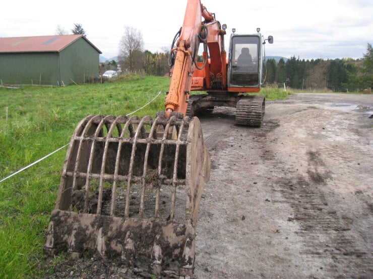Gravemaskin, grønt gras, fjøs, 