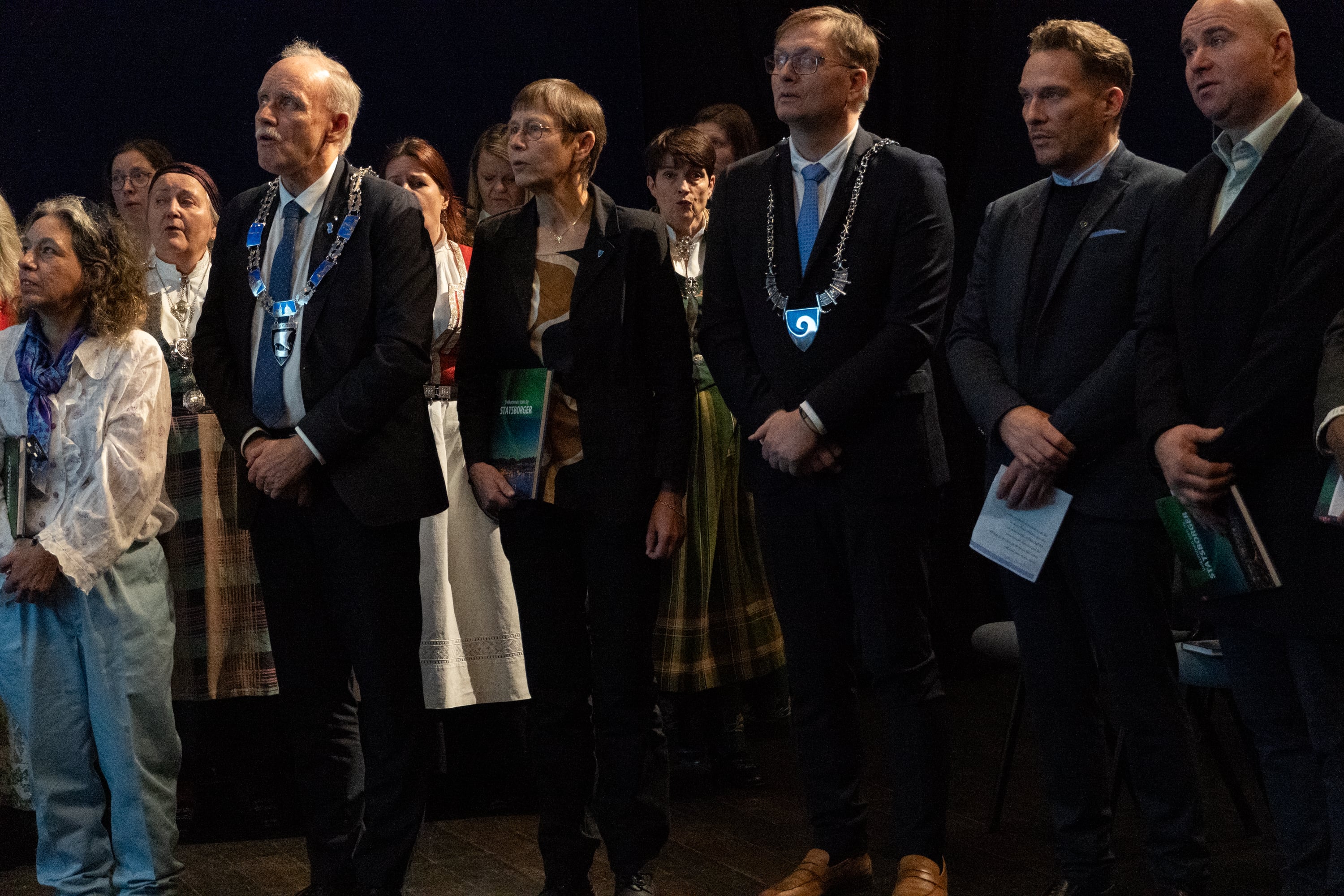 Mennesker i pene klær står og synger.