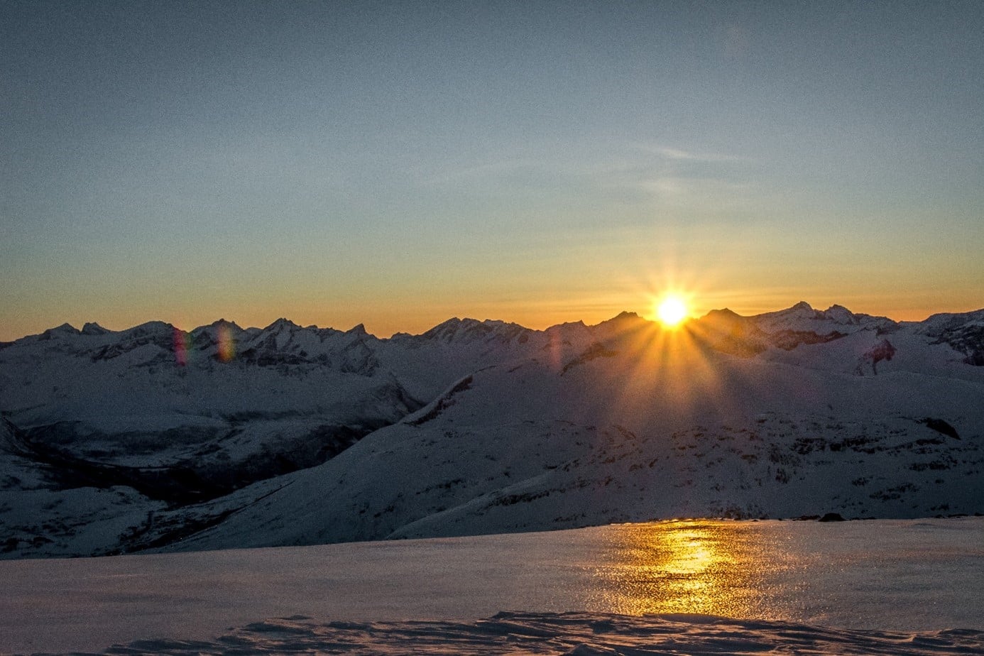 Solen ligger lavt bak fjellene.