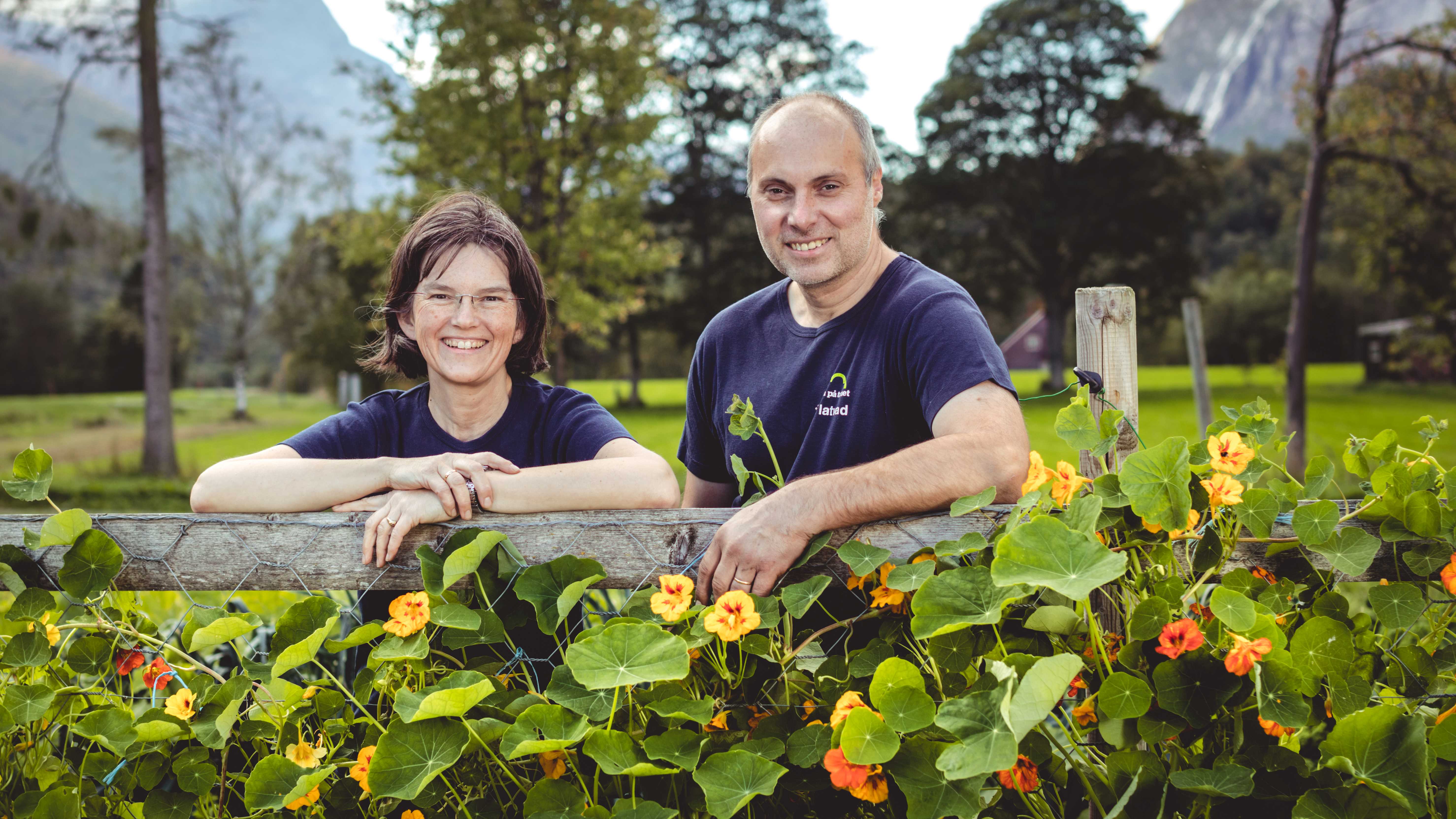 Portrett av Knut og Rita Flatvad i lag med blomster i hagen. 