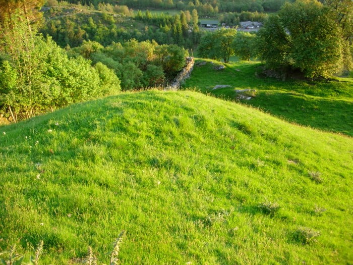 Bilde viser ein jorddekt gravhaug på innmark