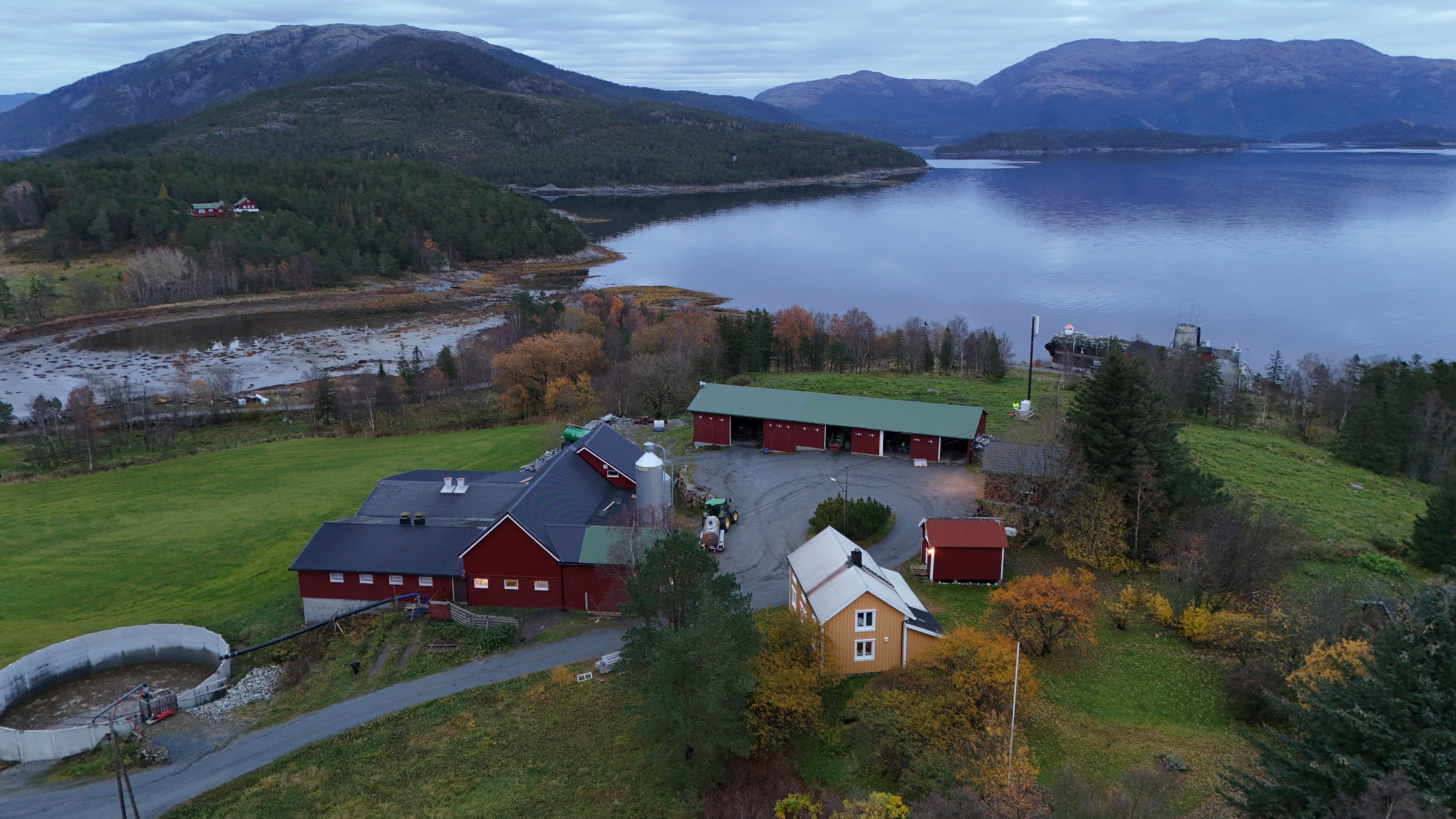 Bilde av gårdstun med fjord og fjell i bakgrunnen