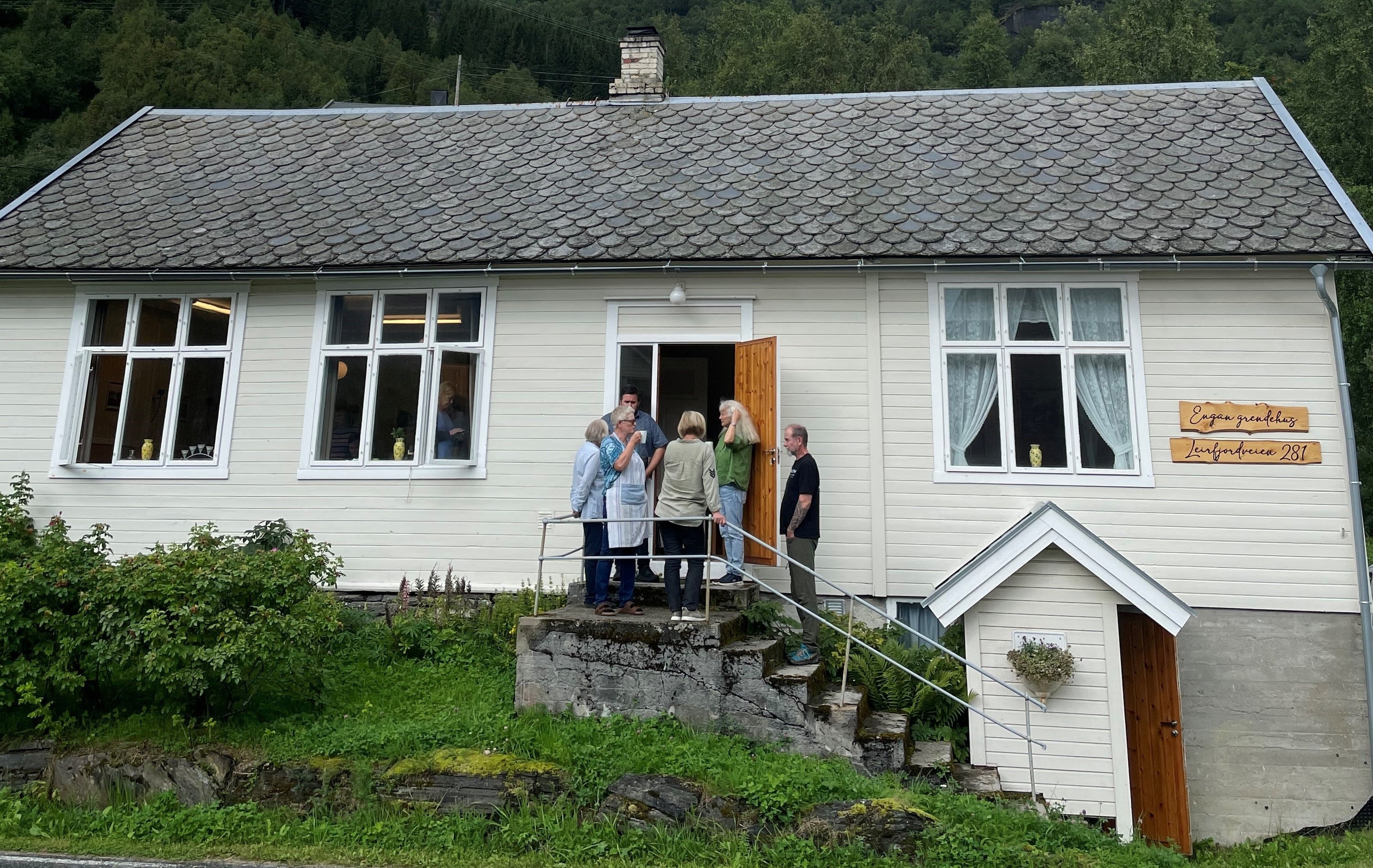folk på trappa til et grendehus 