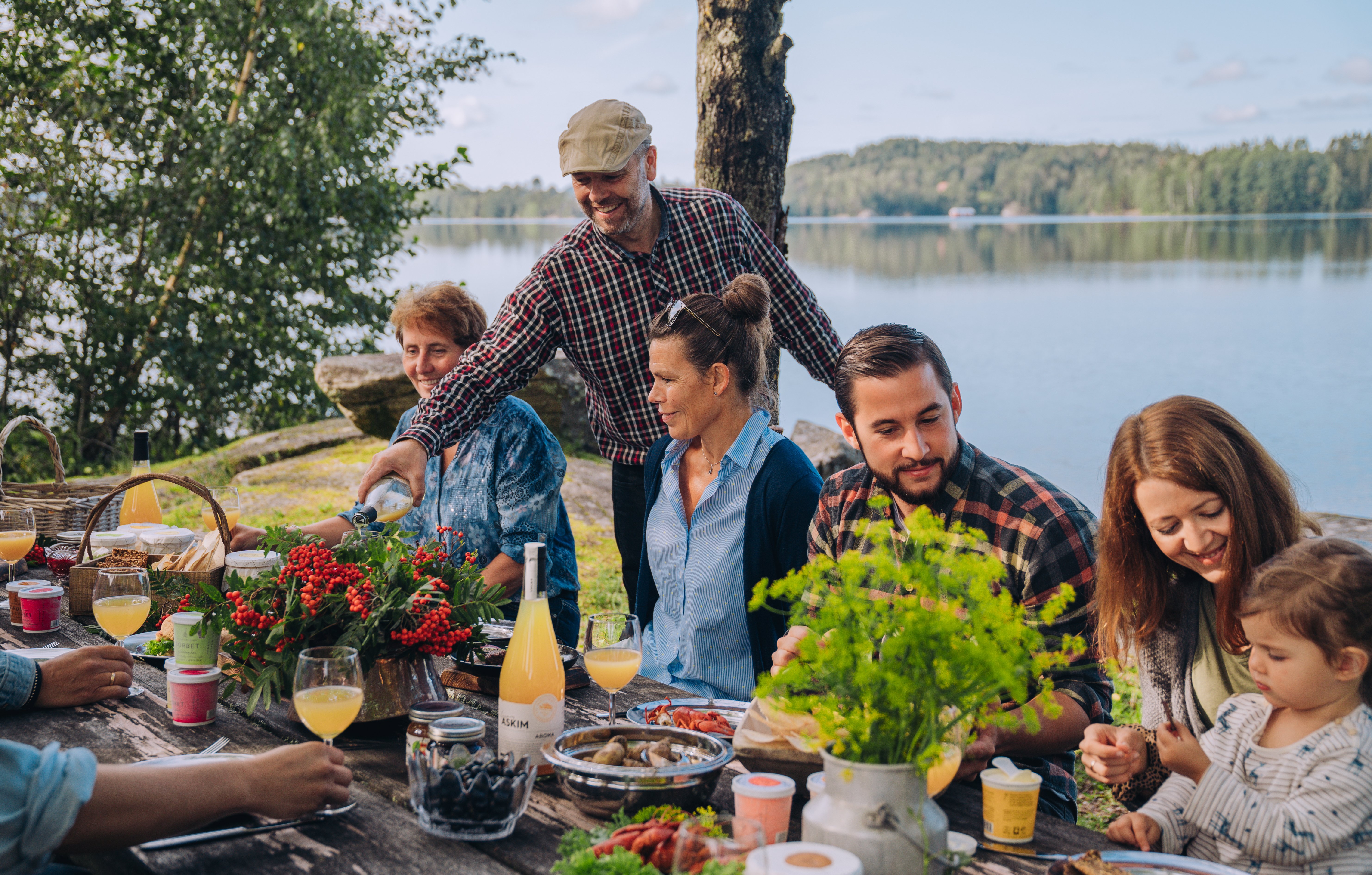 Bilde som viser mennesker rundt et bord, mat og drikke, natur