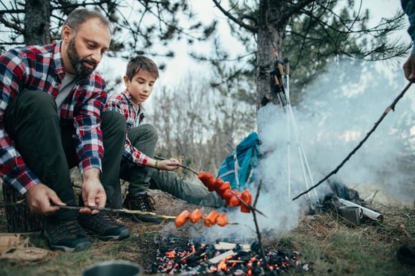 Folk griller mat på et bål i skogen
