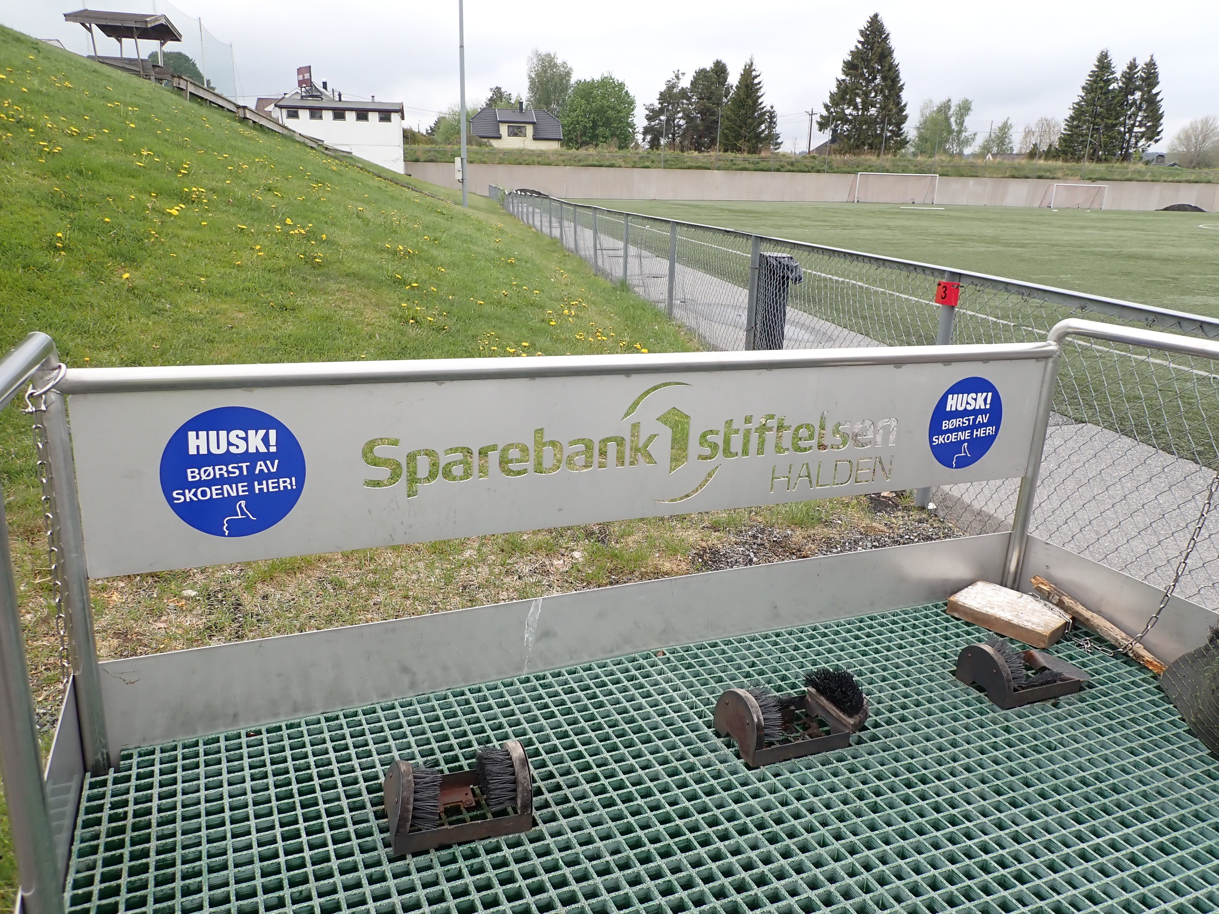Stasjon for å børste gummigraunlat av skoene ved fotballbane.
