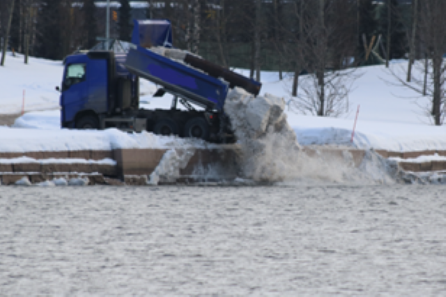 Blå lastebil dumper snø i Drammenselva.