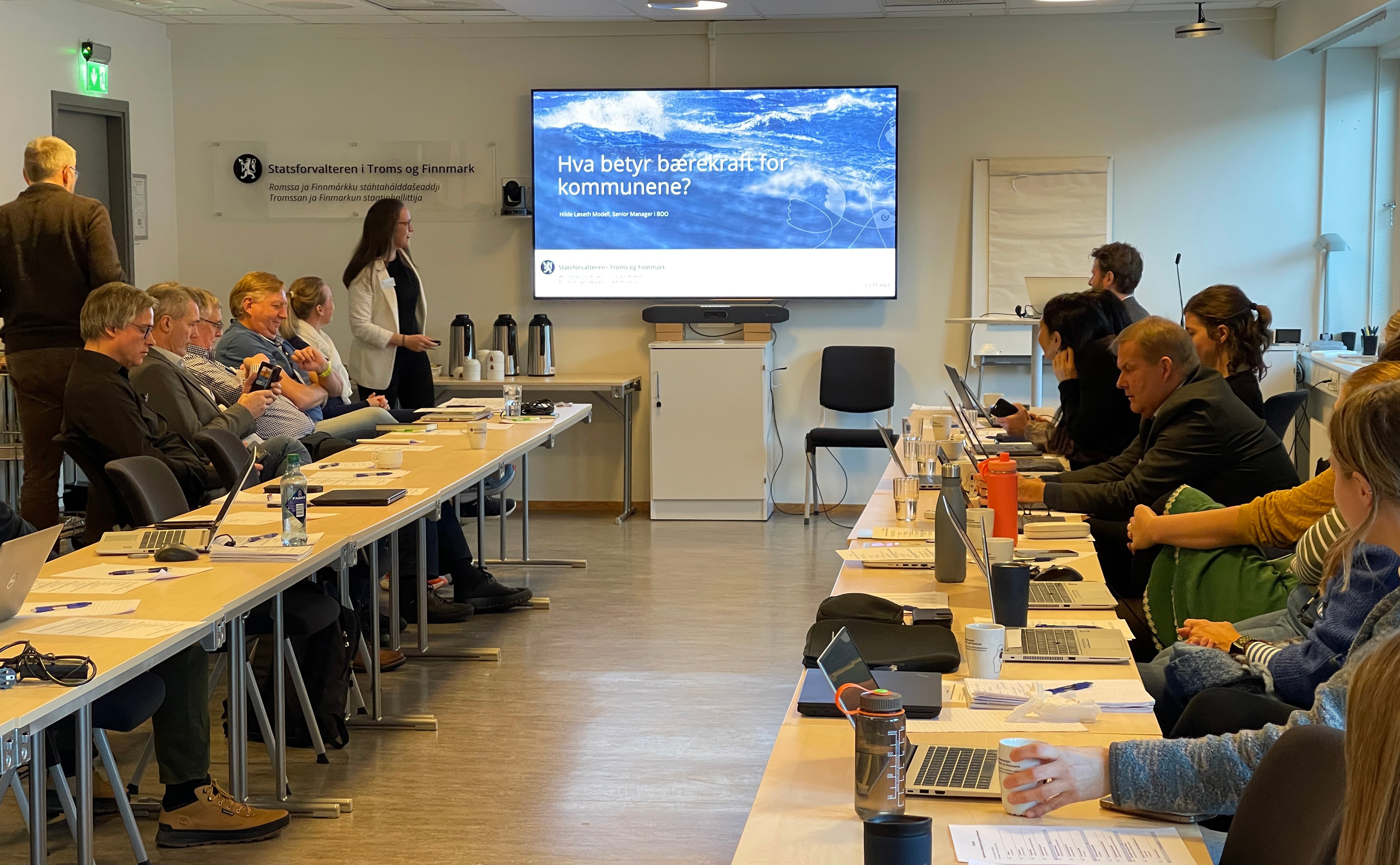 Mennesker i møterom med en presentasjon på storskjerm