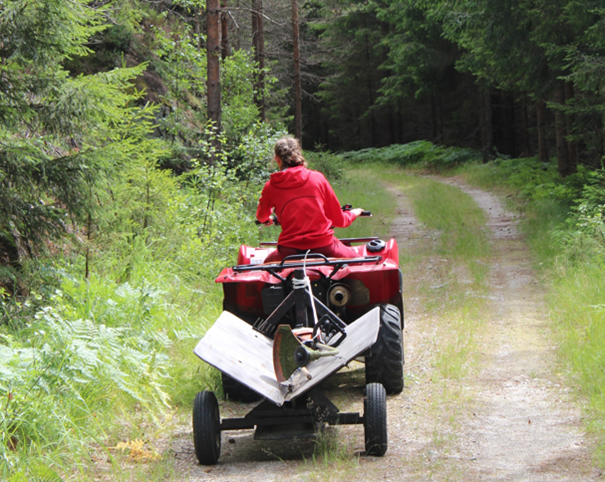 Kvinne som køyrer ATV på ein skogsveg