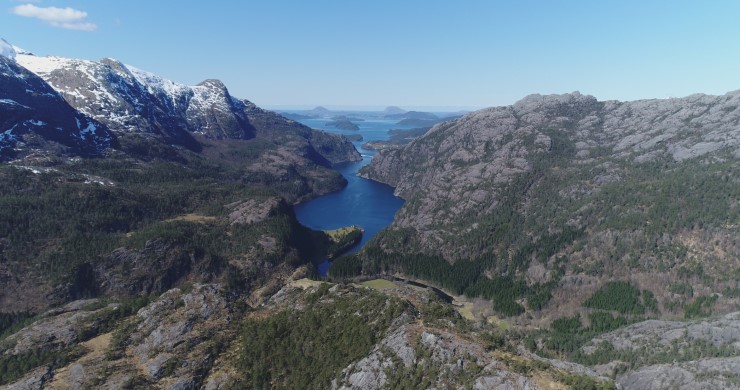 Flyfoto med skog og fjell og utløpet av ei elv