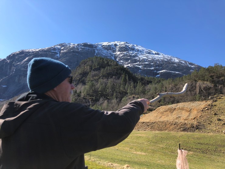 Mann peiker med stokk mot skog
