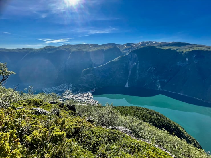 blå himmel og grøn fjord, med eit industrisamfunn inst i ein fjord