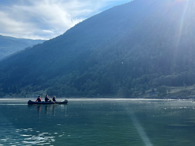 Kano på ein fjord med sol som speglar seg i vatnet