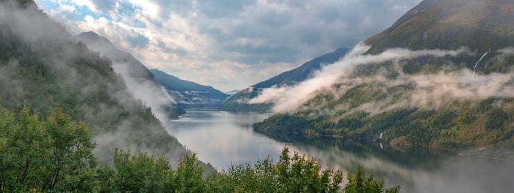 ein fjord mellom grøne lier og litt skyer langs linene