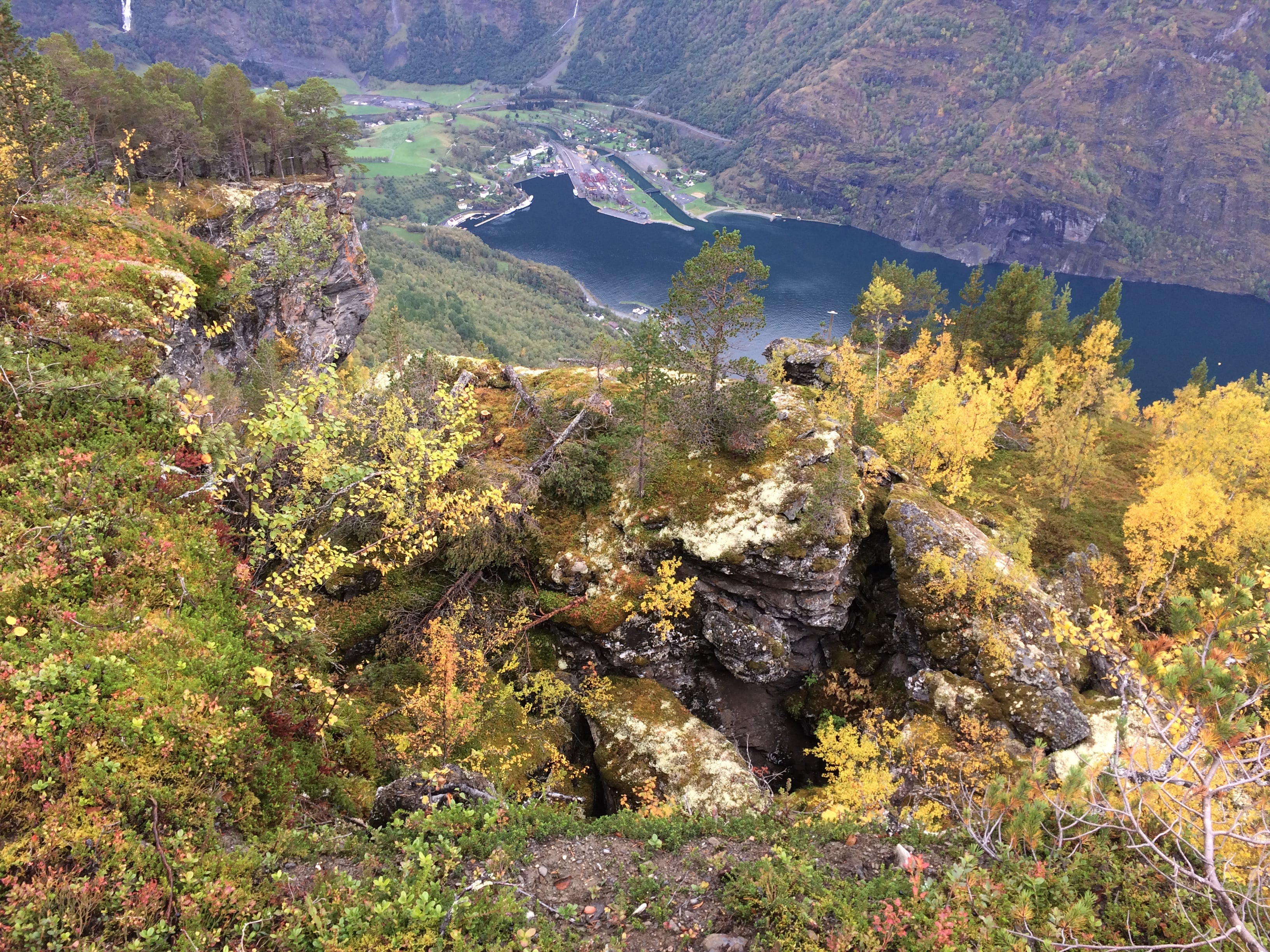 Illustrasjonsbilete tatt frå høgt oppe i fjellside der ein ser ned på fjellpartiet Joasetbergi i Aurland kommune. I bakgrunnen kan ein sjå Flåm sentrum, med hamneområde og litt av fjorden.