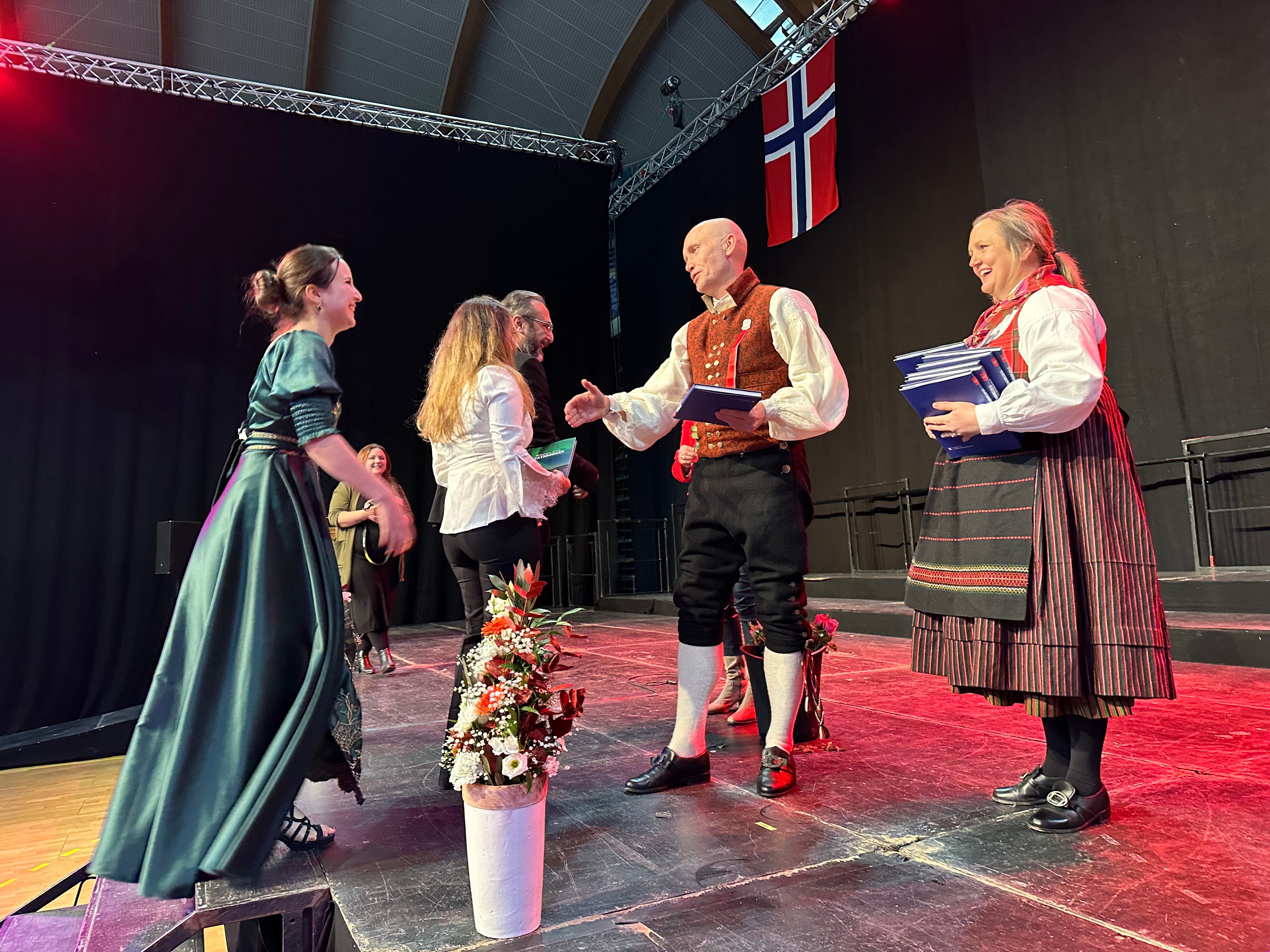 Statsborgere kommer på scenen under seremoni, og statsforvalter håndhilser.