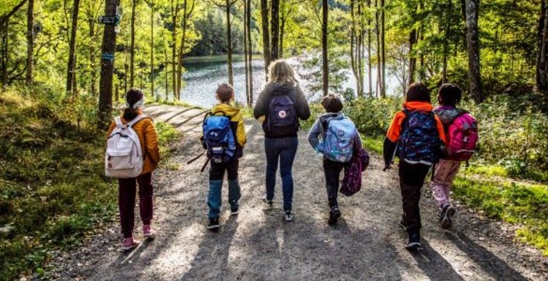 Bilde av skoleelever og voksne som er på tur i skogen