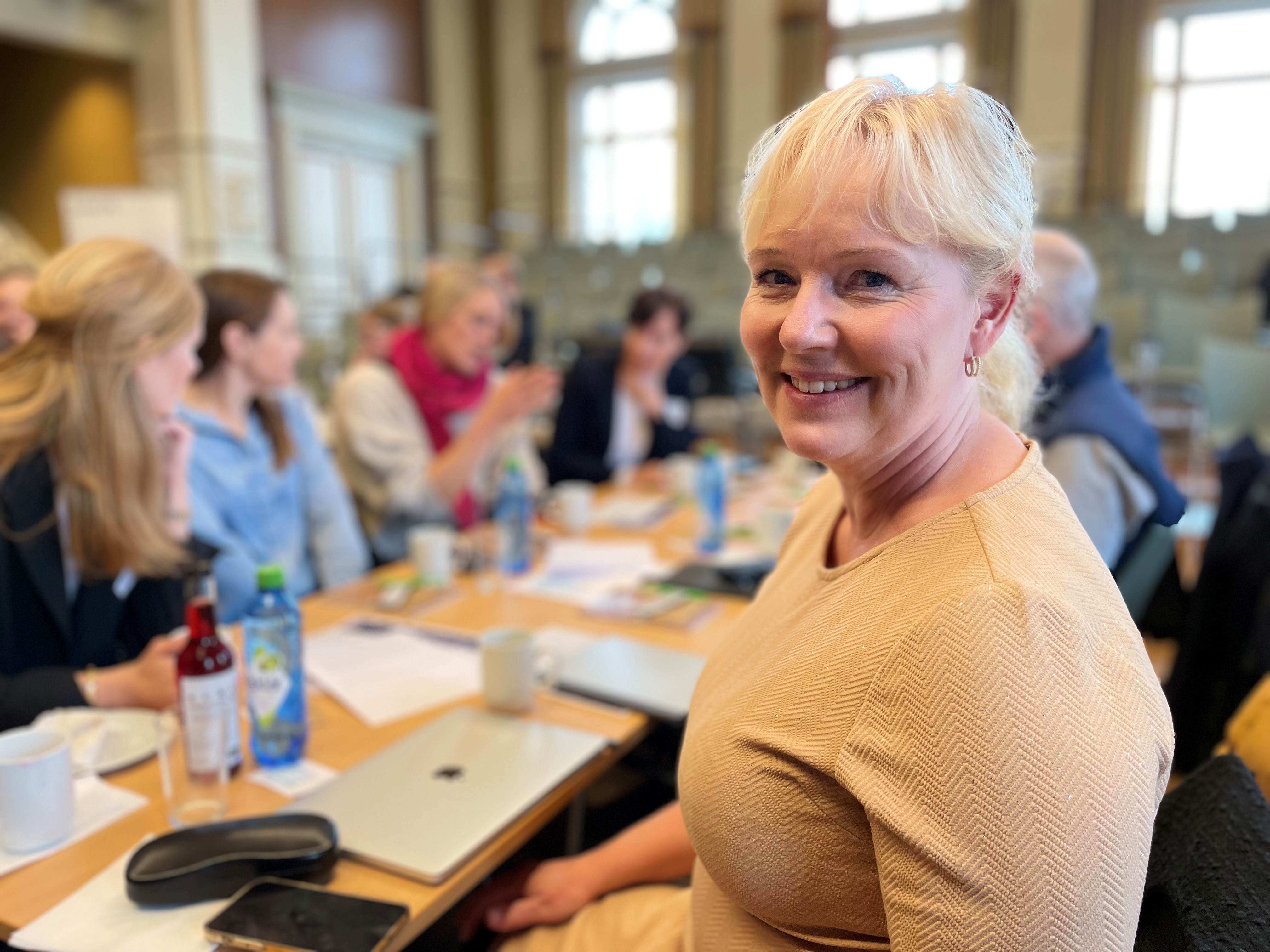 Dame sitter foran en gruppe menneskler som driver med fruppearbneid.