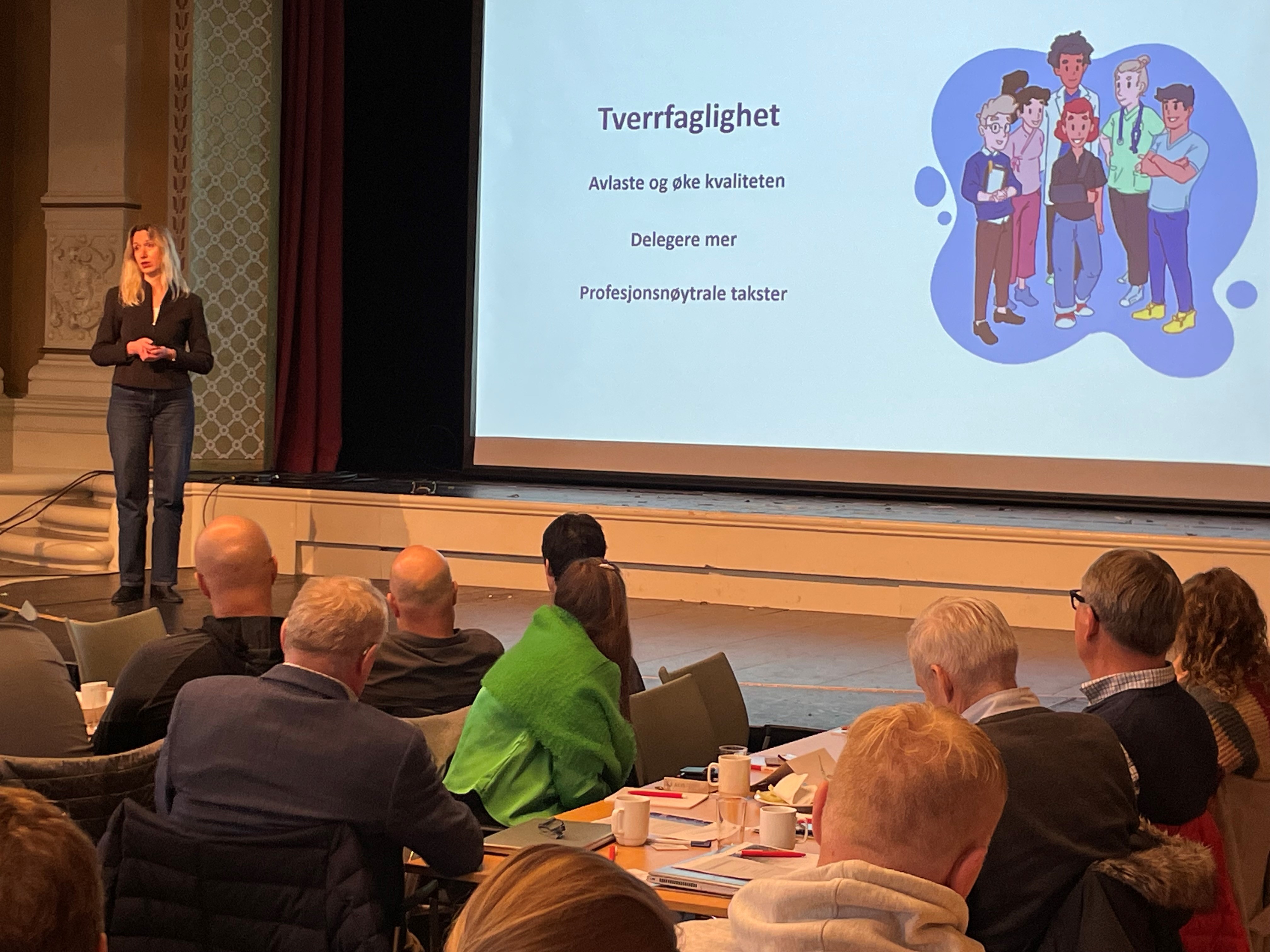 Dame står foran en storskjerm.