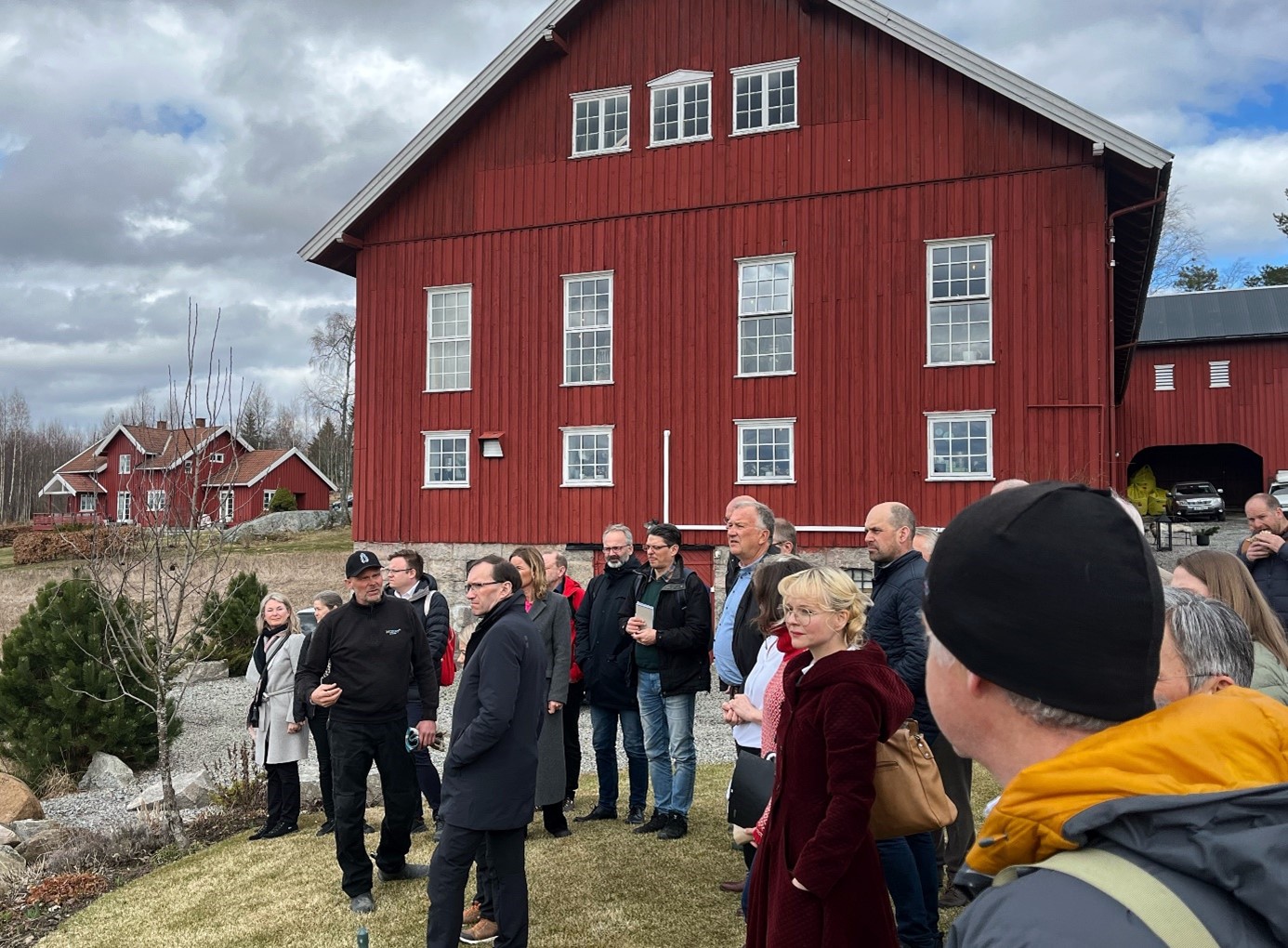 Foto av mennesker ute ved en låve.