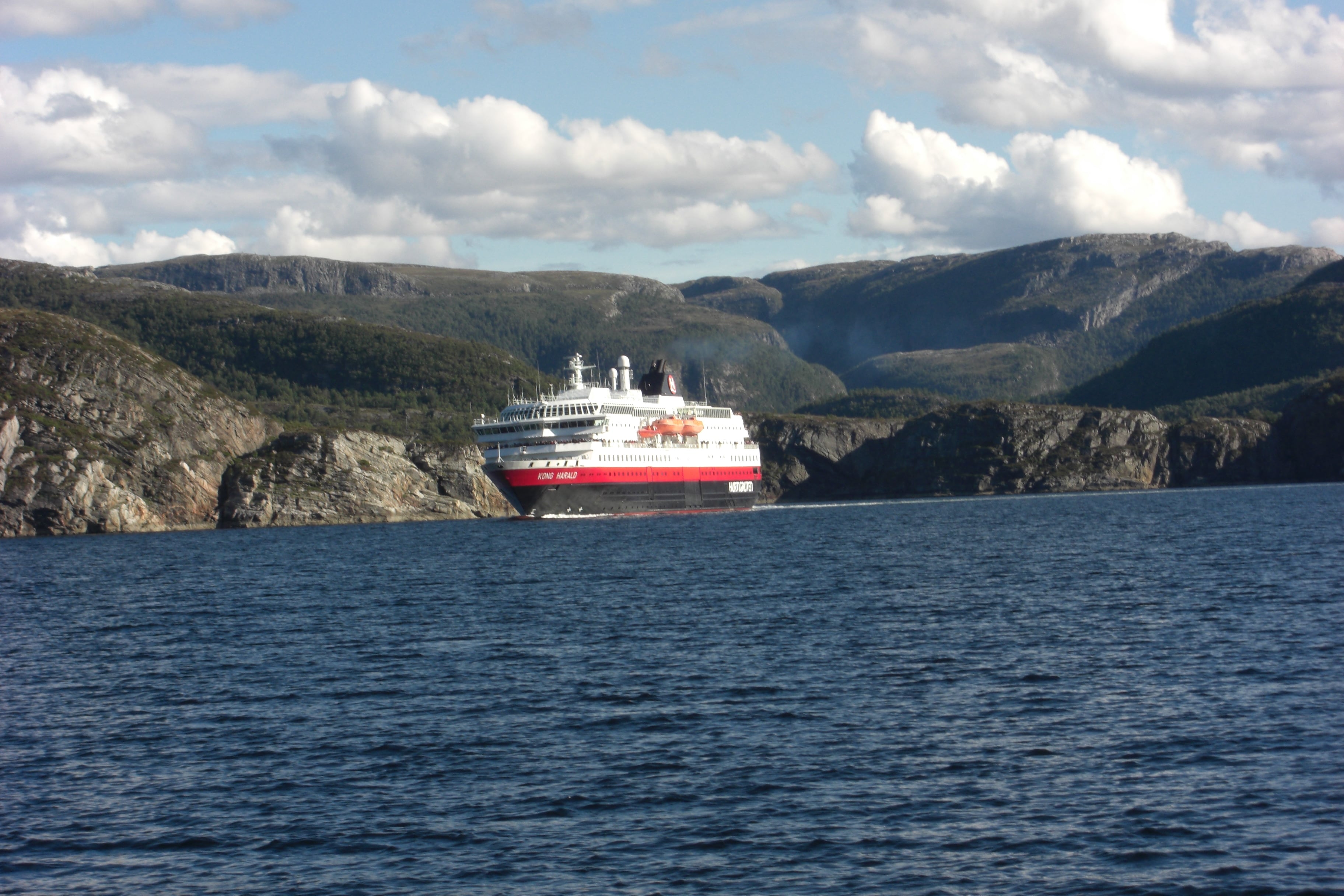 Bildet viser en ferje på havet med fjell i bakgrunnen